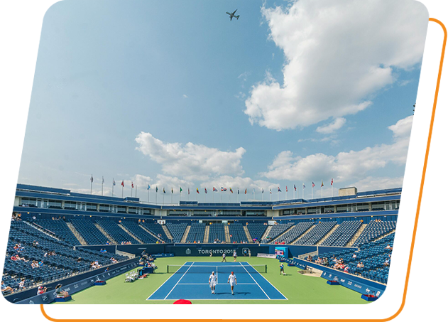 A large tennis court with an airplane flying overhead.